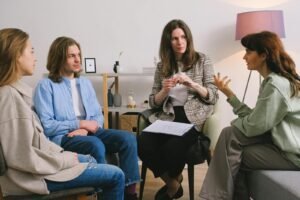 A group therapy session taking place indoors with an attentive counselor guiding the discussion.
